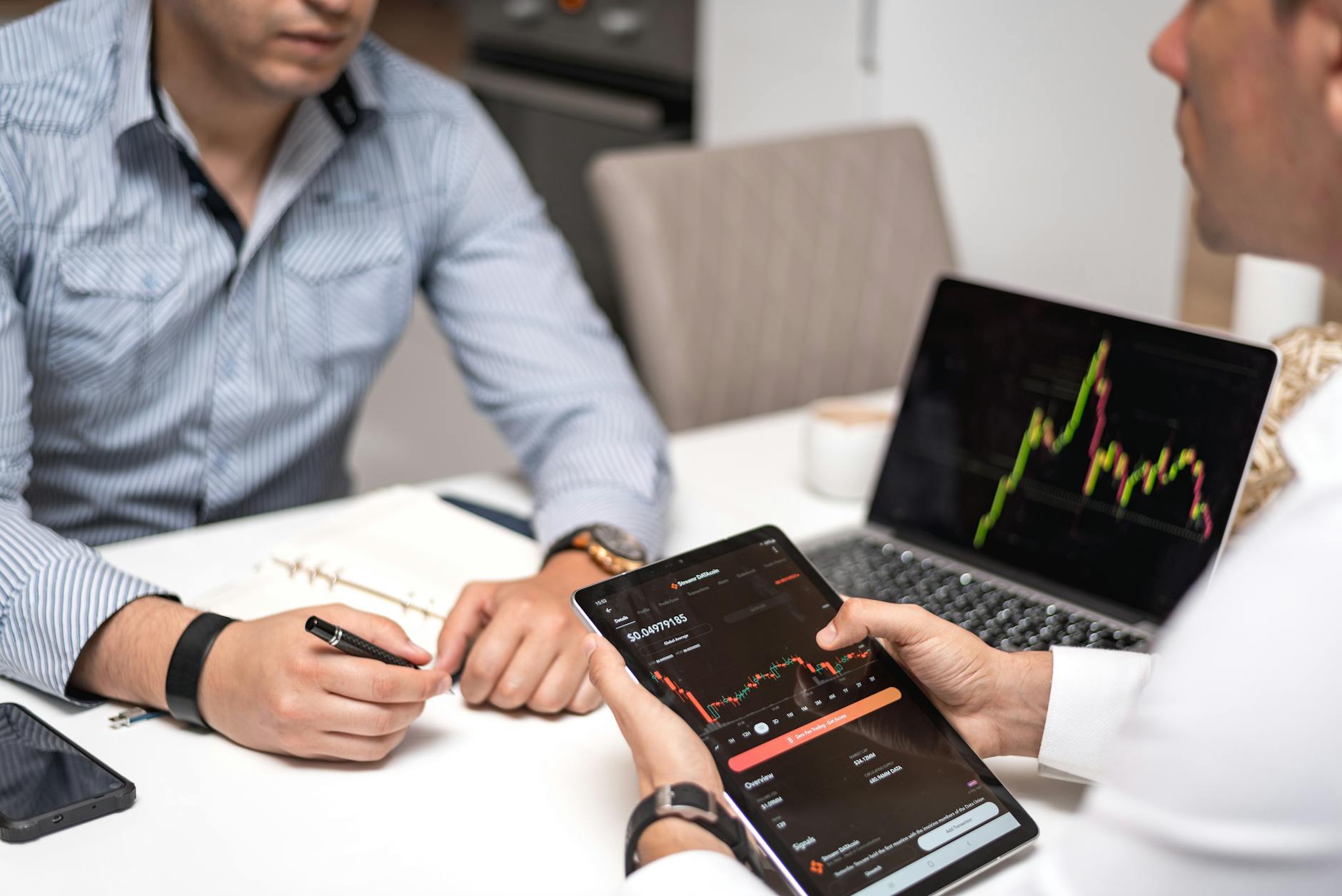 Two professionals discussing crypto trends using digital devices in an office setting.